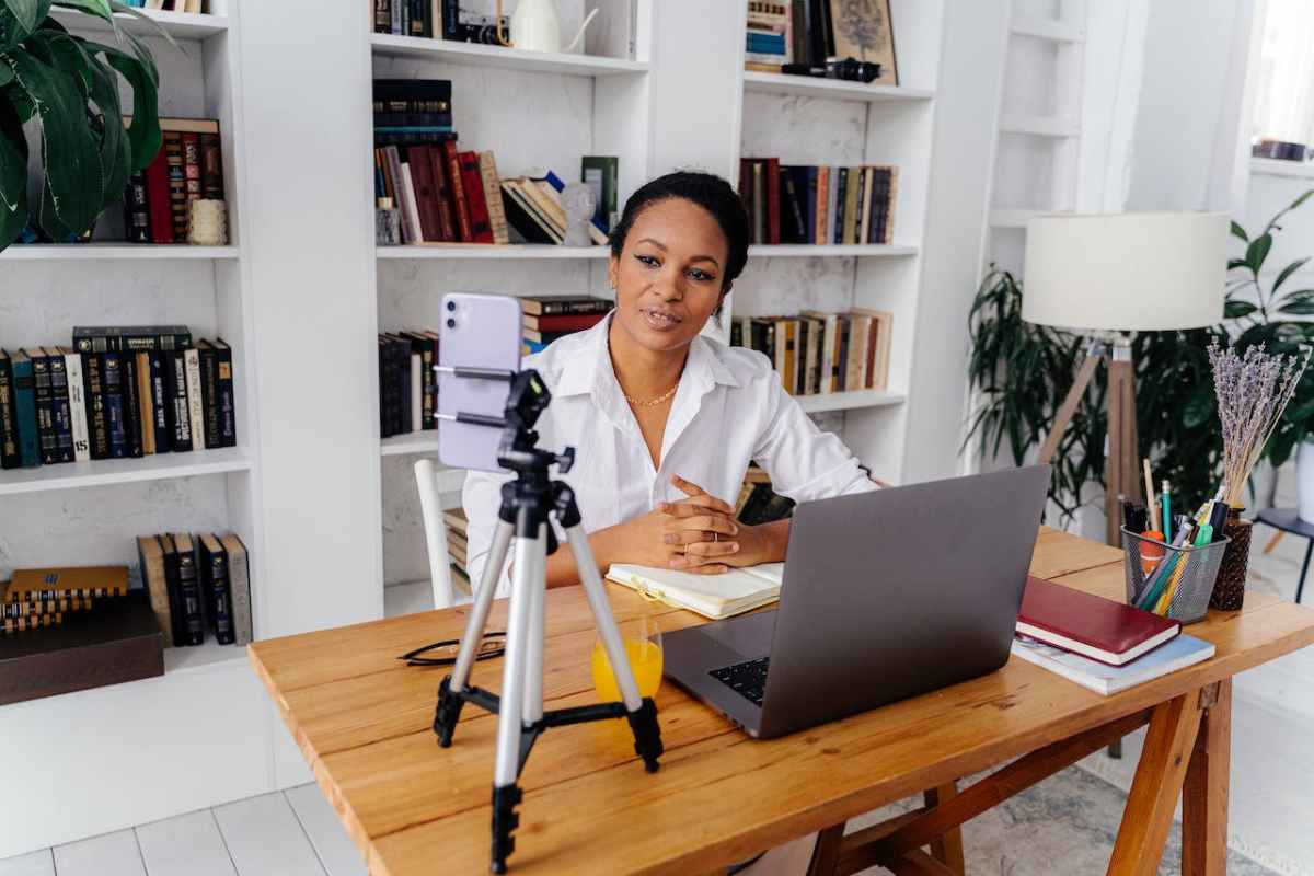 Woman in White Shirt Sitting at Desk with Silver Laptop and Smartphone